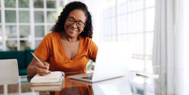 Smiling senior writing in journal at home